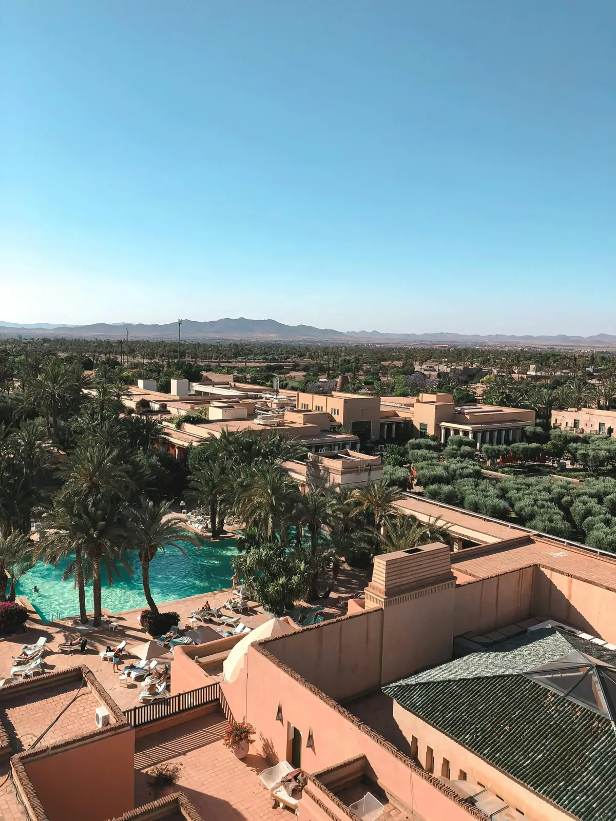 Vue panoramique de villas de luxe à la Palmeraie de Marrakech avec piscines et palmiers.